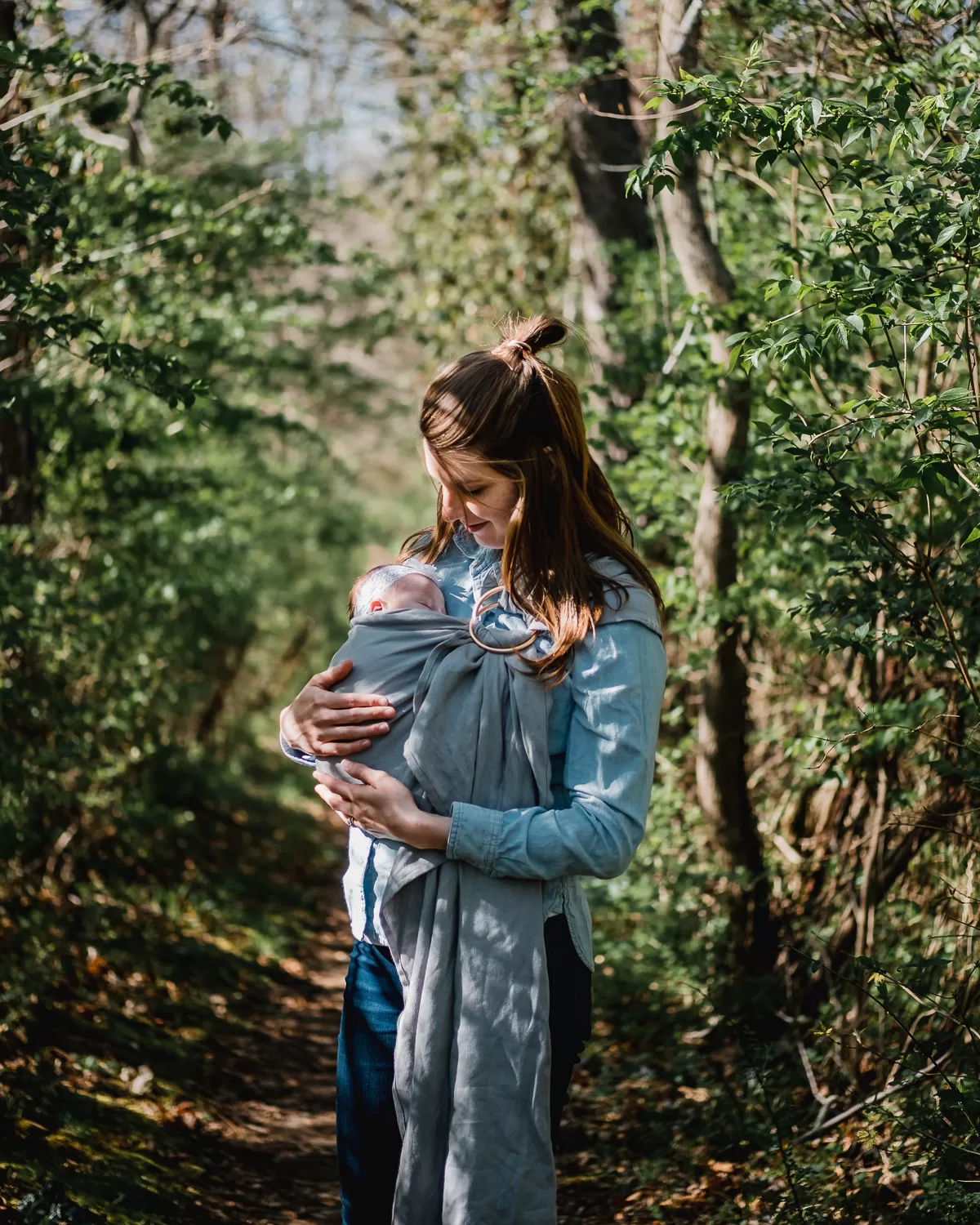 mom holding baby in cloth carrier in orchard by kyle nieber