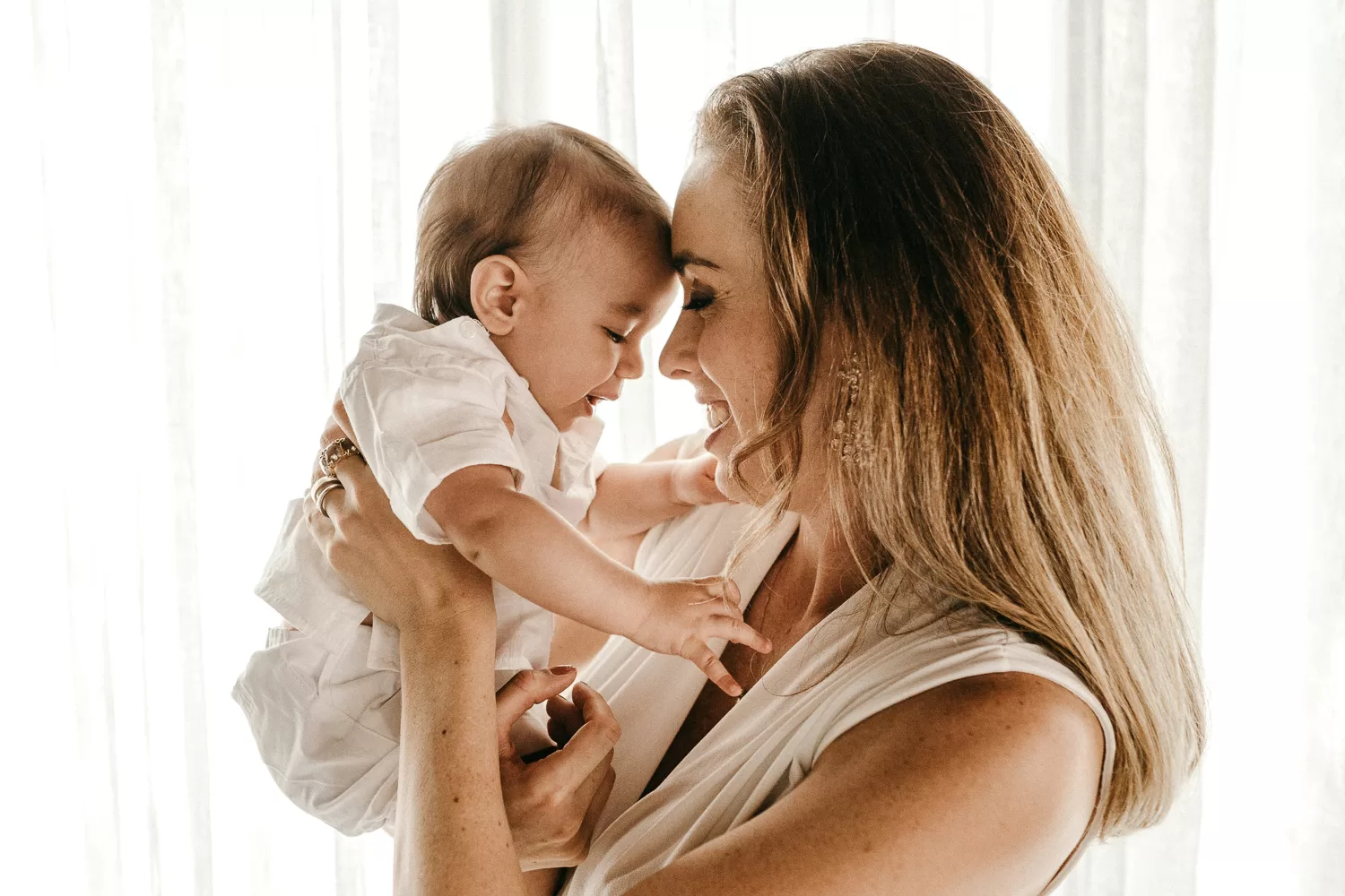 mom holding newborn close to her forehead and smiling